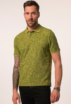 Grünes Poloshirt mit einem dezenten Blattmuster, kurzärmlig und mit klassischem Kragen. Der Stoff hat eine strukturierte Oberfläche. Schwarze Hose und Uhr sind sichtbar.