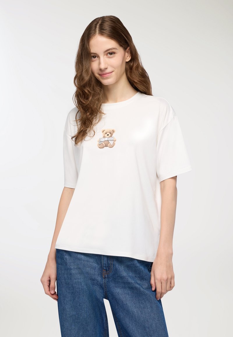 Biała koszulka z krótkim rękawem z haftowanym misiem na piersi. Wykonana z miękkiego materiału, o luźnym, swobodnym kroju.