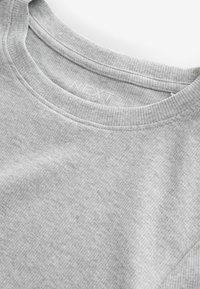 Sweatshirt gris à col rond fabriqué en tissu texturé et côtelé. Présente un motif subtil et le nom de la marque "NEXT" imprimé à l'intérieur du col.