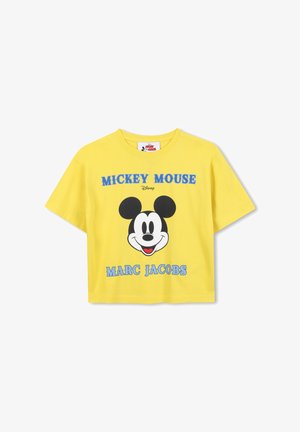 T-shirt en coton jaune cropped arborant un grand imprimé noir et blanc de Mickey Mouse, avec "MICKEY MOUSE" et "MARC JACOBS" en texte bleu.
