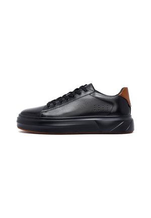 Sneaker en cuir noir avec semelle épaisse, bout rond, lacets noirs et tirant en cuir brun, présenté de profil sur fond blanc.