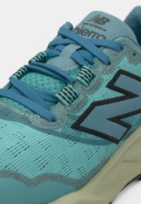 Αθλητικό παπούτσι σε υδάτινο μπλε με επάνω μέρος από δίχτυ, επίπεδα κορδόνια, υφασμένα διακοσμητικά στοιχεία και μαύρο λογότυπο "N" στο πλάι. Μαλακή, επενδεδυμένη σόλα.