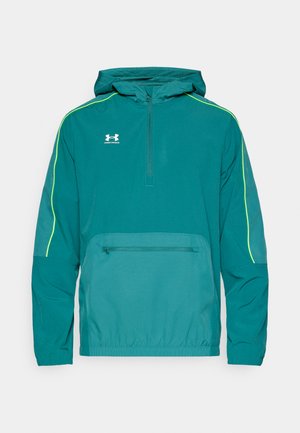 Tirkīzzils pelēks ar kapuci, ar ceturkšņa rāvējslēdzēju, kontrastējošu dzeltenu šuvi, priekšējā kabata un elastīgu apakšu. Izgatavots no viegla auduma.