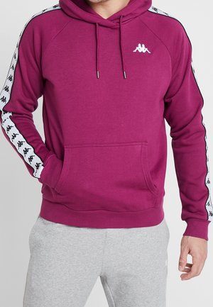 Bordowa bluza z kapturem z przednią kieszenią, z białymi paskami po bokach i czarnym nadrukiem logo. Wykonana z miękkiego materiału, z przytulnym kapturem ze sznurkiem.