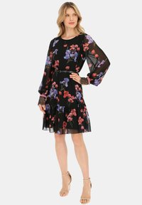 Czarna sukienka w kwiaty z fioletowymi i czerwonymi wzorami. Przezroczyste długie rękawy i falbaniasty dół. Zawiera wąski pasek w talii i koronkowe mankiety.