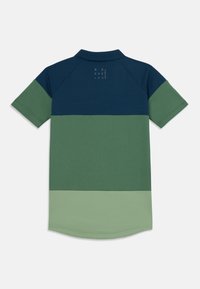 Polo tričko s barevným blokem designu v námořnické, tmavě zelené a světle zelené barvě. Měkká textura s jemným recyklovaným logem.
