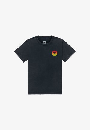 T-shirt en coton bleu marine avec un logo DC, short en denim, et baskets noires et blanches avec des accents rouges. Coupe décontractée, manches courtes.