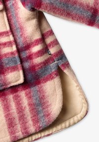 Couverture en laine à carreaux dans des teintes beige, rouge et grise ; texture douce ; dispose d'une doublure lisse de couleur claire et de bords cousus.