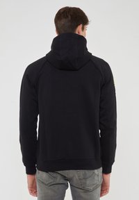 Felpa nera con cappuccio, con orlo e polsini a coste, dotata di tasca a marsupio e design posteriore senza cuciture. Tessuto morbido e TEXTURATO.