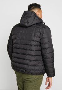 Sort puffet jakke med hætte, prydet med vandrette syninger og en glat tekstur. Bagsiden viser en afslappet pasform og minimal detaljer.