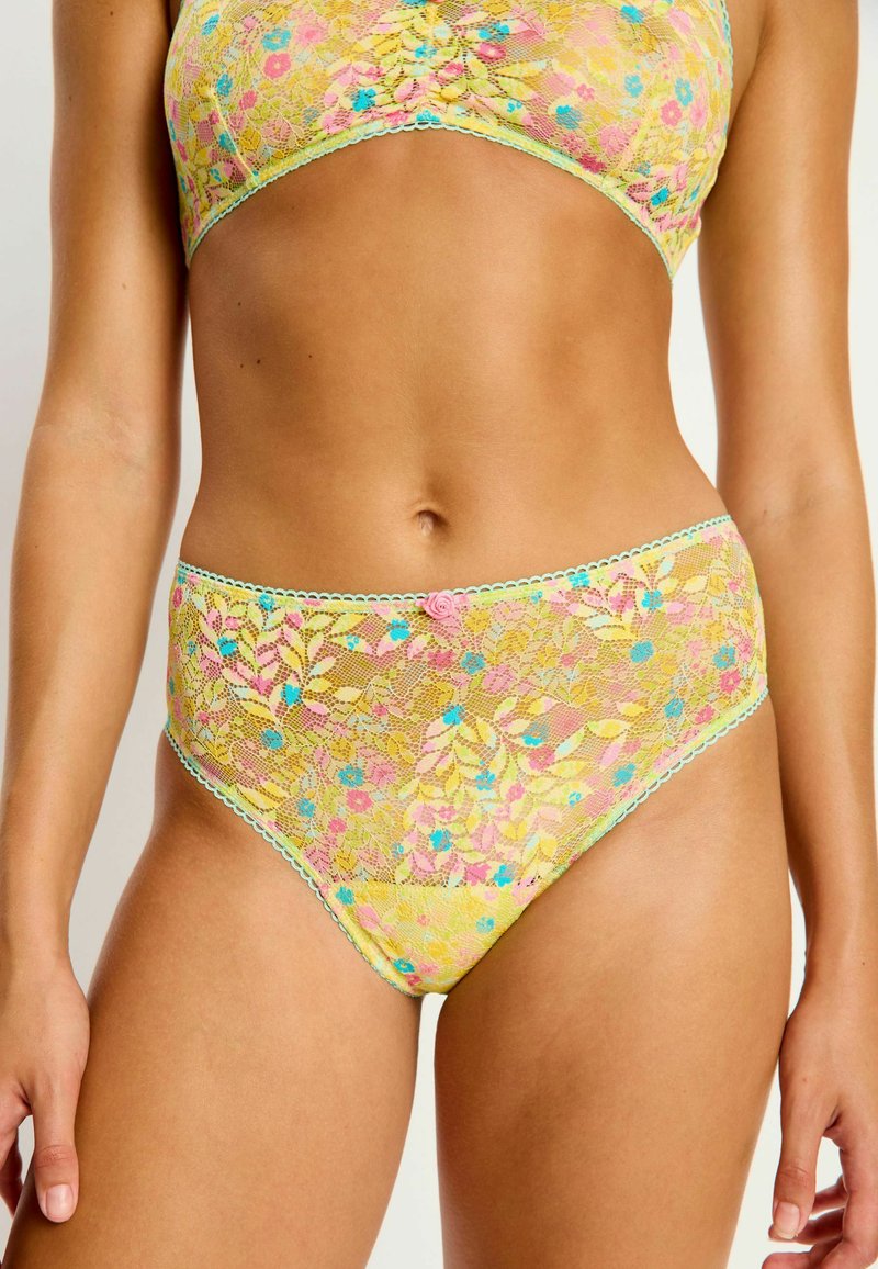 Ensemble de lingerie en dentelle jaune avec des motifs floraux ornés d'accents roses et bleus. La taille est dotée d'une bordure délicate à volants.