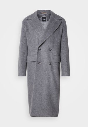 Gray herringbone overcoat with a large lapel, double-breasted design, and two front pockets. Made of textured, warm fabric.