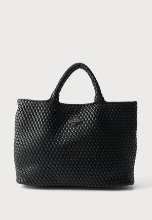Sac cabas tissé noir avec deux anses et une petite plaque logo en forme de diamant centrée près du haut.