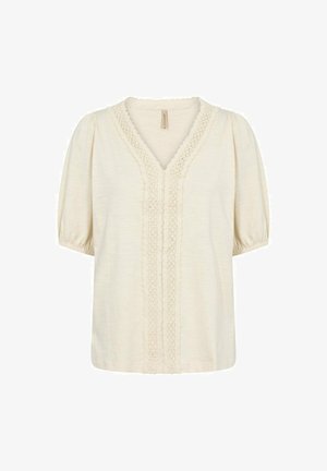 Krémová blúzka s výstrihom do V a čipkovým lemovaním na prednej strane. Má krátke pufové rukávy a mäkkú, štruktúrovanú látku.