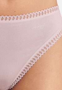 Lyserøde bomuldsunderbukser med bølget blonderkant. Glat tekstur med et tætsiddende design og diskret mærke på linningen.