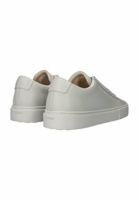 Zapatillas de piel gris claro con un diseño minimalista, suela de goma blanca plana y cierre con cordones. Presenta un logo sutil en el talón.