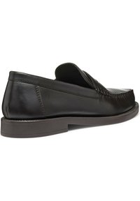 Donkerbruin lederen instap schoen met een gladde afwerking, ronde neus en subtiele stiksels. Flat rubberen zool met bescheiden hoogte.