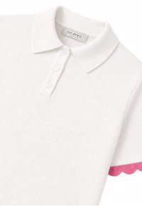 Polo blanc à manches courtes avec trois boutons blancs et un col, avec une bordure festonnée rose sur le bord de la manche.