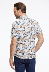 Camicia a maniche corte con stampa floreale su sfondo bianco, caratterizzata da fiori arancioni e blu, foglie verdi e un colletto dritto. Vista posteriore mostrata.