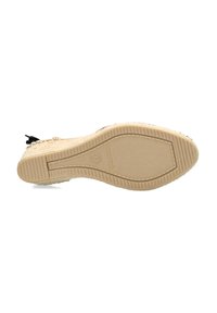 Suola della scarpa con fondo in gomma texturizzato. Materiale beige con superficie pattern e un piccolo accento nero. Etichettatura visibile sul tallone.