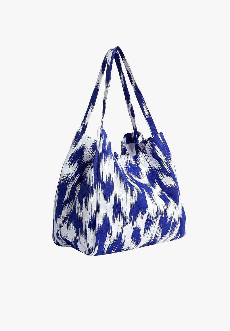 Blue and white patterned fabric tote bag with two sturdy handles, a wide opening, and a soft, textured finish.