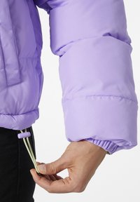 Doudoune lavande luminescente avec un cordon de serrage à l'ourlet. La manche possède un poignet élastique et une finition lisse et brillante.