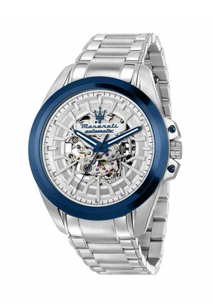 Orologio da polso automatico da uomo Maserati con cinturino in metallo argentato, lunetta blu, quadrante scheletrato e ingranaggi e viti visibili.