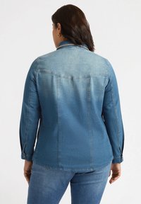 Jasnoniebieska kurtka dżinsowa z długimi rękawami, z mankietami zapinanymi na guziki oraz efektem wyblaknięcia. Posiada klasyczny kołnierz oraz detale w tylnej części.