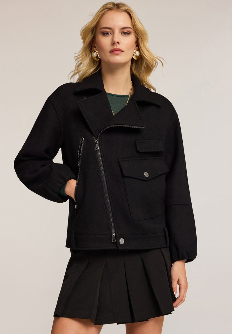 Zwarte wolmix jas met een grote kraag, ritssluiting en voorzak. Heeft een comfortabele pasvorm en ribgebreide manchetten.