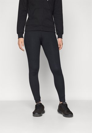 Svarte leggings laget av elastisk materiale, tettsittende design, glatt tekstur, kombinert med svarte treningssko og en matchende zip-up hettegenser.