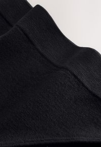 Tissu noir avec une texture lisse et un motif côtelé sur le bord, présentant un design plié. Convient à diverses applications vestimentaires.