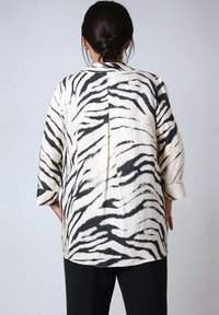 Crème en zwarte zebraprint blouse met lange mouwen, met een losse pasvorm, voorzien van een rugsplit en zachte, gestructureerde stof.