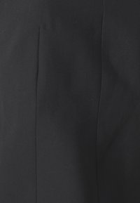 Tissu noir avec une texture lisse et un éclat subtil. Il y a un détail de couture verticale sur le côté gauche, contribuant à une apparence épurée.