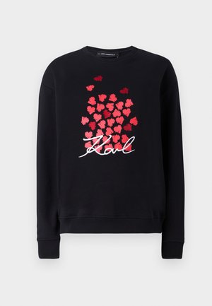 Black sweatshirt with long sleeves, featuring a cluster of red heart shapes and the word "Karl" in white cursive lettering on the front.