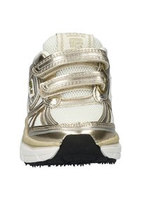 Witte sportieve schoen met metallic gouden accenten, bovenwerk van mesh, klittenband straps en een zwarte rubberen zool; kenmerkt zich door een gestructureerd ontwerp.
