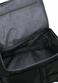 Borsa nera in nylon con un interno spazioso, dotata di chiusura a zip e fodera grigia con motivo a rilievo del logo "GUESS".