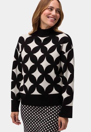 Black and white sweater featuring a geometric leaf pattern, long sleeves, and a high neckline. Textured fabric with a fitted waistband.