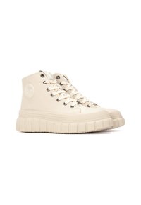 Zapatillas altas beige con suela de goma texturizada, puntera redonda y ojales de metal. Presenta un logo circular en el lado exterior.