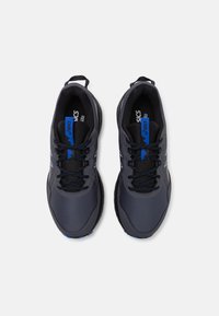 Baskets de sport noires et bleues avec une tige en maille, un design texturé, des lacets et une semelle en caoutchouc. Marque sur la languette et sur le côté.