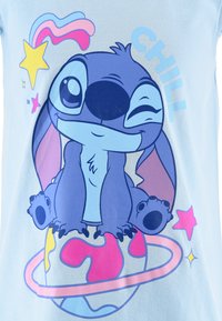 Niebieska bawełniana koszulka z nadrukiem kreskówkowej postaci siedzącej na kolorowej kuli ziemskiej, otoczonej gwiazdami i tęczowymi akcentami, z napisem "CHILL".