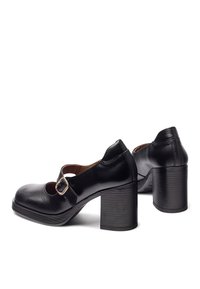 Schwarze Lederabsatzschuhe mit offener Spitze, seitlichem Schnallenverschluss und einem klobigen Absatz. Glatte Oberfläche mit dezenten Nähdetails.