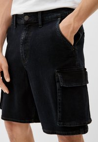 Schwarze Jeansshorts mit normaler Passform, Knopfverschluss, Seitentaschen und einer großen Cargo-Tasche am linken Bein. Strukturiertes Material.