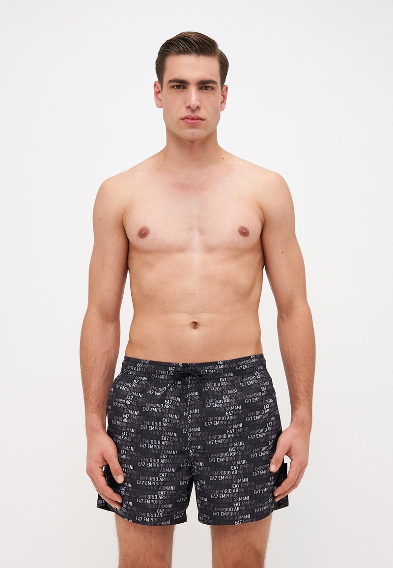 Fekete úszónadrág, ismétlődő fehér "EA7 EMPORIO ARMANI" logómintával. Rugalmas derékpánt zsinórral, könnyű anyag.