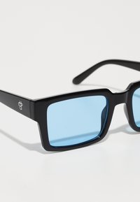 Ochelari de soare negri cu rame unghiulare și lentile de culoare albastră deschisă. Prezintă un mic logo pe braț. Textură netedă și finisaj lucios.