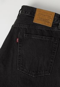 Πίσω τσέπη σε μαύρο τζιν από denim με το κόκκινο ταμπελάκι της Levi's και ταν δερμάτινο λογότυπο Levi Strauss & Co. στη ζώνη.