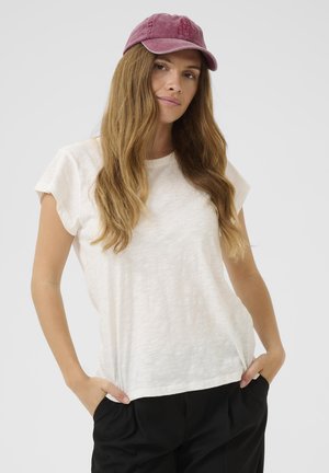 T-shirt bianca a maniche corte con una finitura morbida e testurizzata, abbinata a un cappellino bordeaux. La t-shirt ha una vestibilità rilassata e una scollatura tonda.