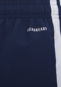 Navy blue shorts with a stretch waistband and white side panels; features "AEROREADY" logo printed on the front. Smooth, lightweight fabric.