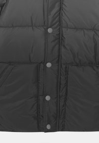 Chaqueta de plumas negra con un diseño acolchado, cierre frontal con botones a presión y bolsillos laterales con un acabado suave y brillante.