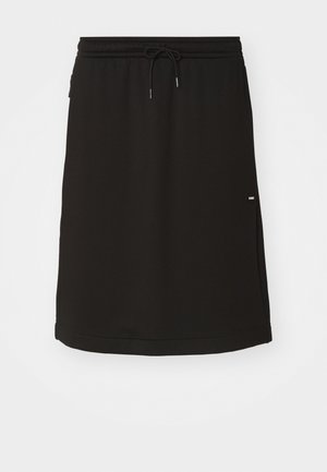 Svart idrettsskjørt laget av mykt stoff. Har en elastisk midjebånd med snor og en liten logo-tag på siden.