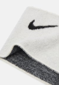 Berretto Nike in tessuto bianco lavorato a maglia, con logo nero. L'interno presenta una fodera in fleece grigia e testurizzata. Design morbido e flessibile.